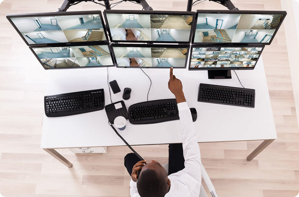 man pointing at security monitors